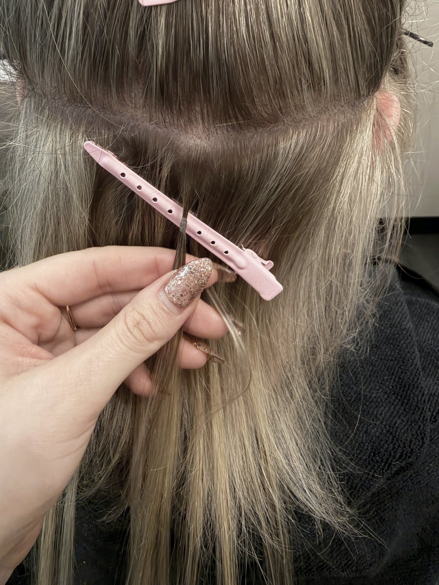 Megan placing a keratin bond along a parted row
